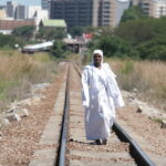 An Apostolic woman walks along train tracks on her way back from a mountain prayer session.