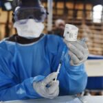 A health worker prepares to administer Ebola vaccine outside a house in the village of Mangina