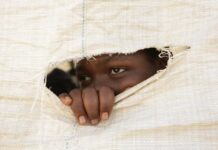 ‘My family had no business selling me off for R4’ A Zimbabwean secondary school student peeps through a hole in a sack that forms the wall of a makeshift classroom.