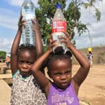 Girls carry bottled water in Maputo